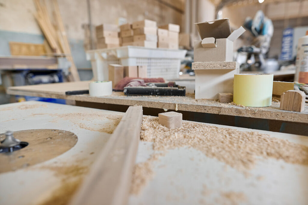 Joinery workshop with timber on the workbench, sawdust, and a craftsman working in the background