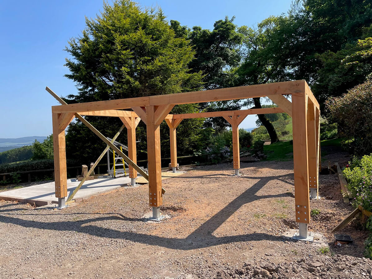 timber car port frame with knee braces and open structure, set against Perthshire countryside