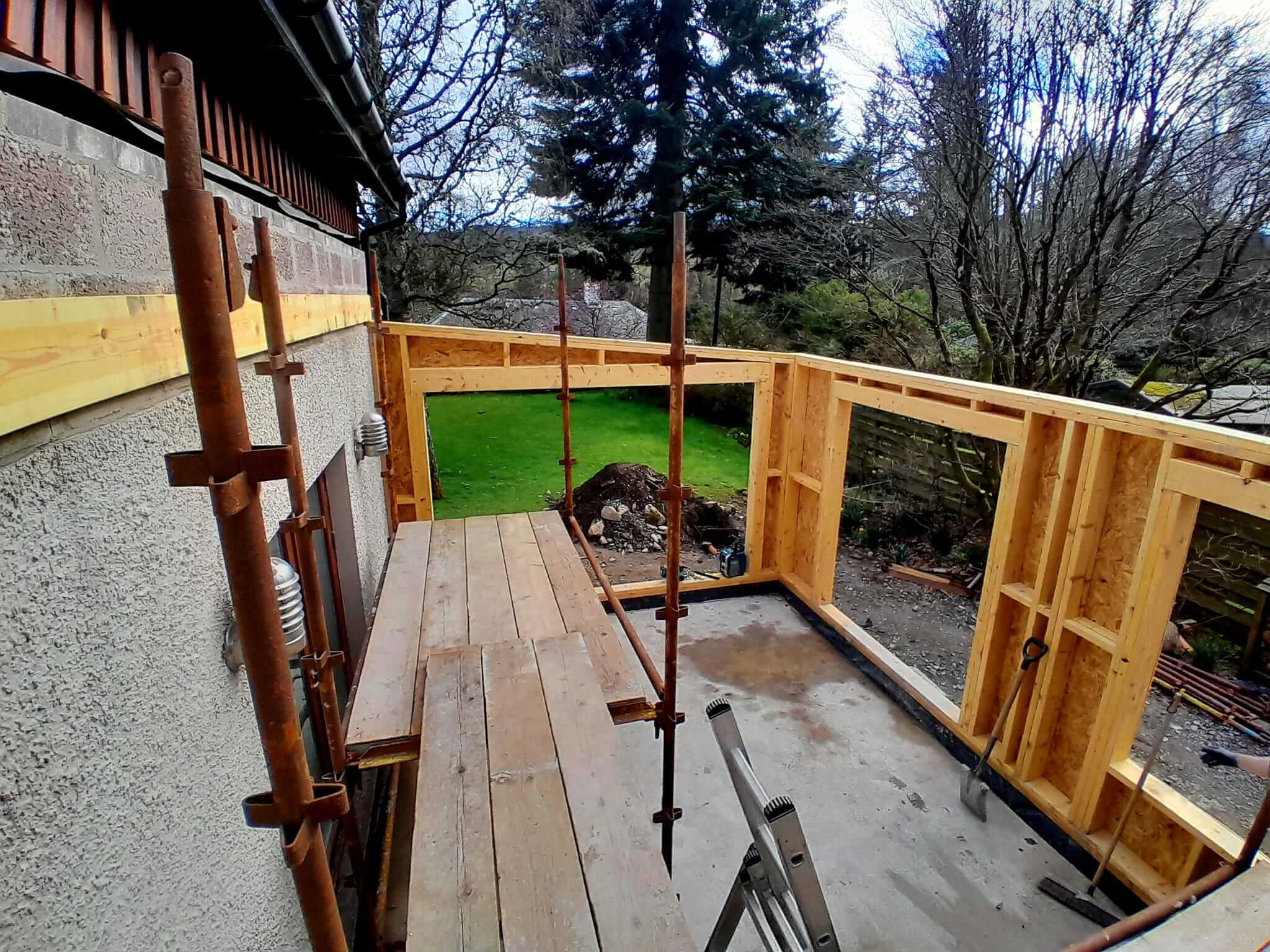 Timber frame extension walls under construction viewed from scaffold, looking out over garden, Weem