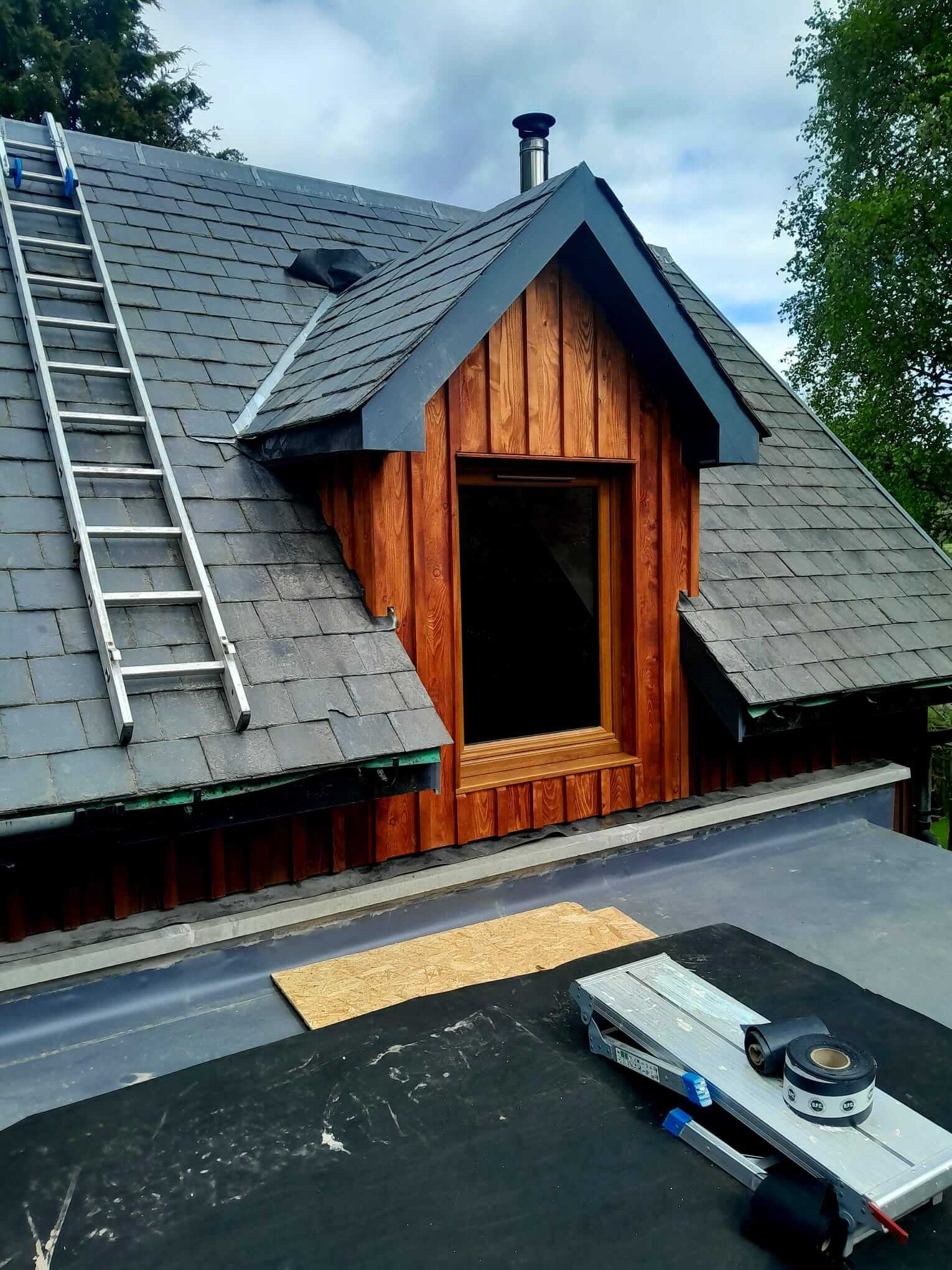 Completed larch-clad dormer gable on main house with new timber-framed window, EPDM flat roof membrane laid on extension below