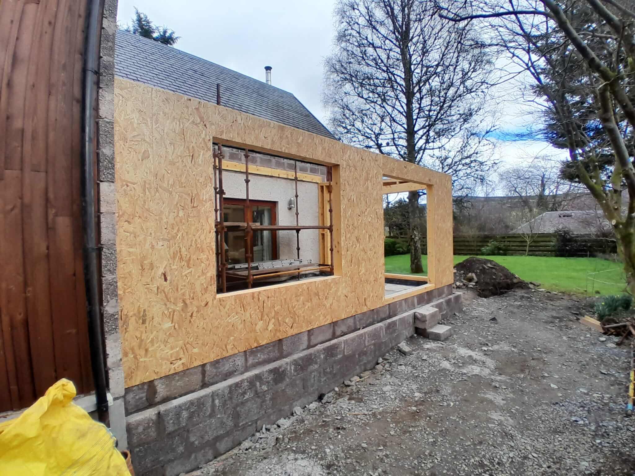 OSB-sheathed timber frame gable and side wall with large window opening, block foundation course, Weem extension