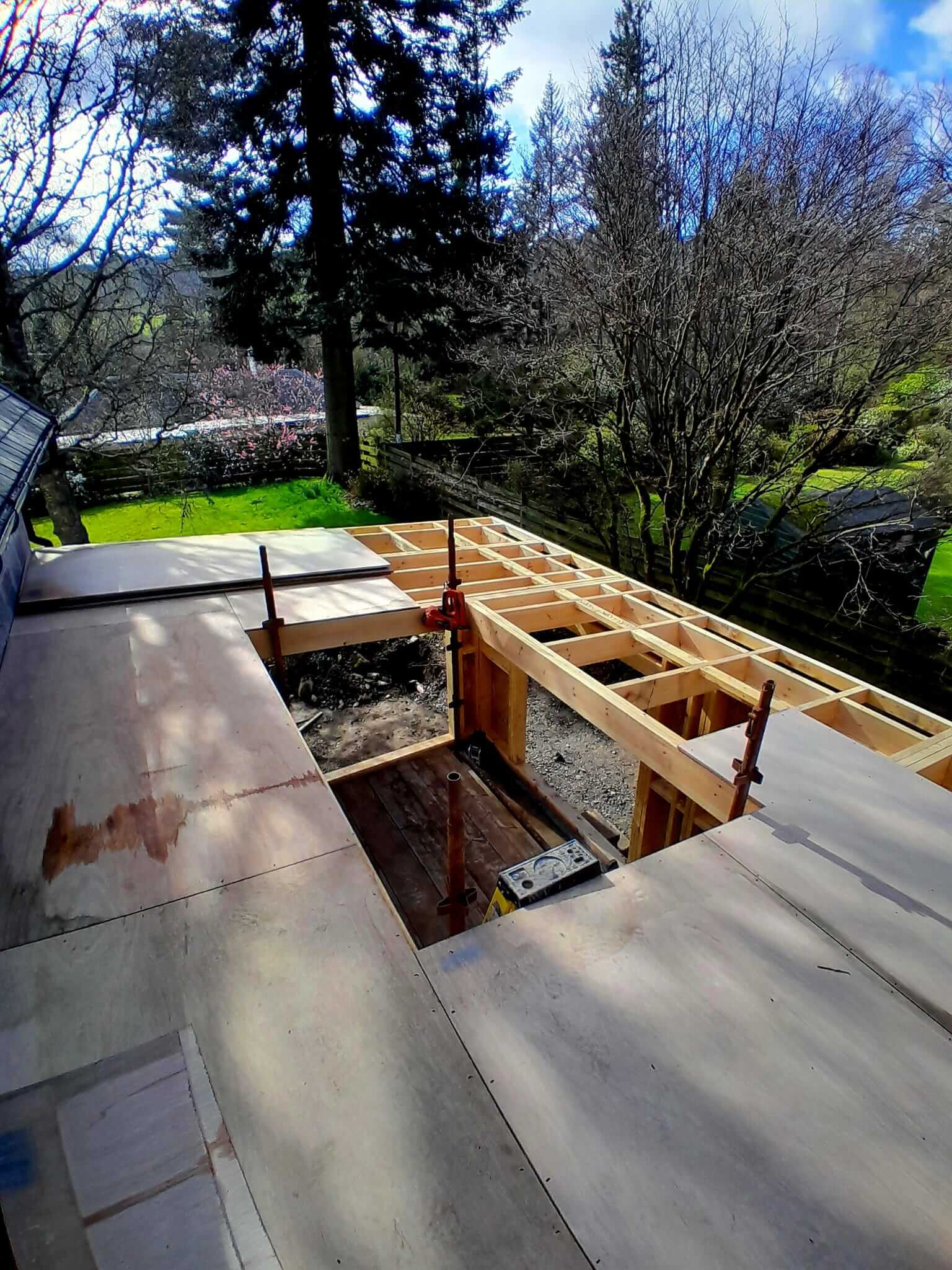 Flat roof deck partially boarded with rooflight curb framed out, aerial view of extension construction