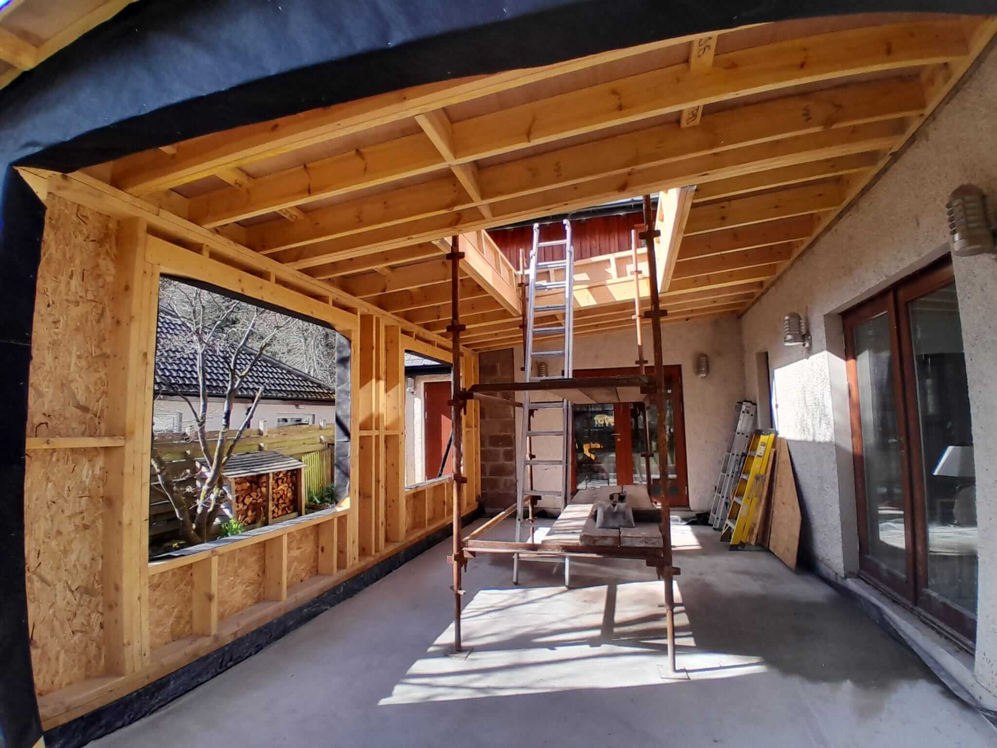 Interior of extension showing exposed timber ceiling rafters and open rooflight void above polished concrete floor