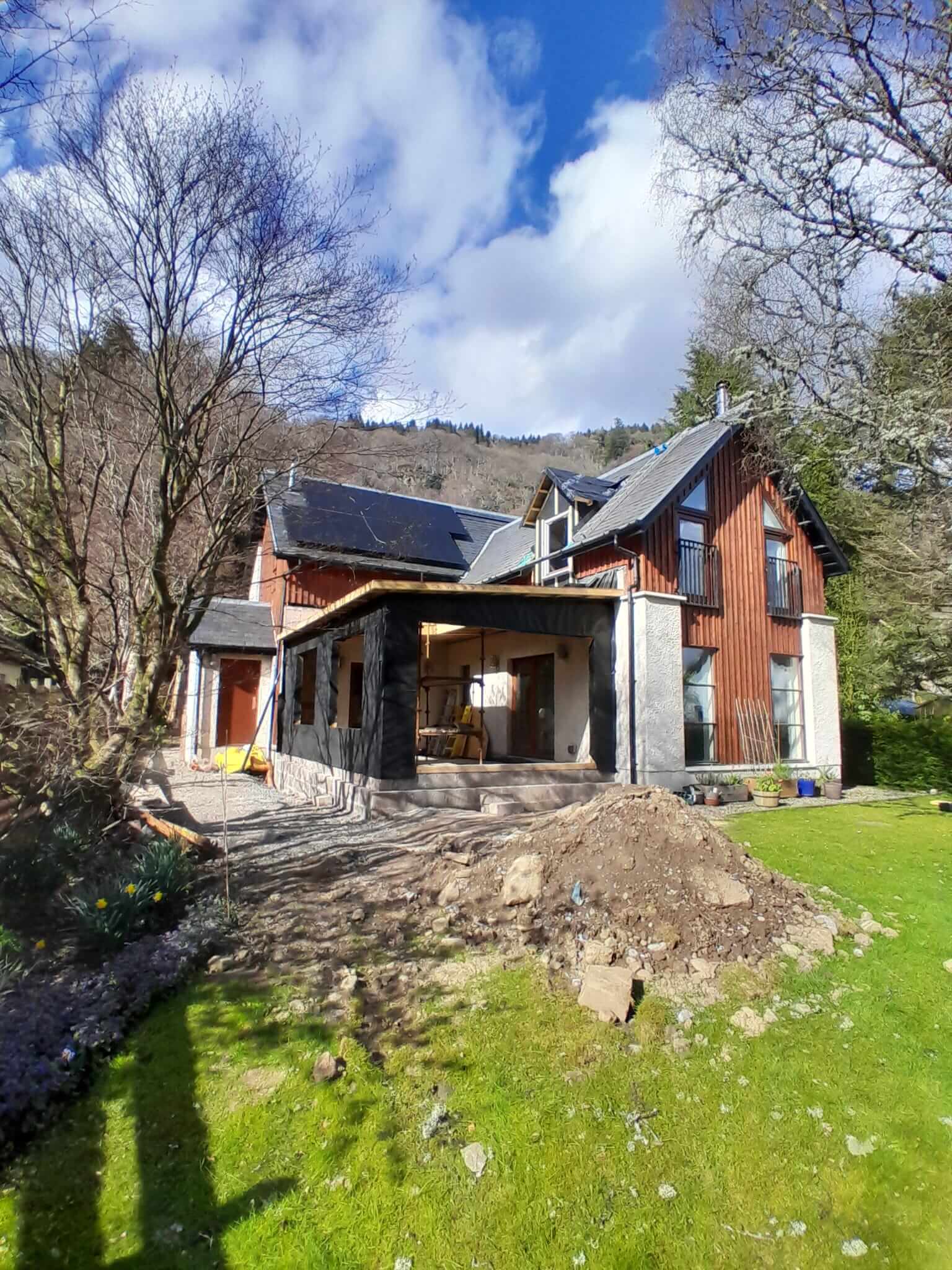 Exterior of extension with dark breather membrane applied, flat roof complete, anthracite glazing frames visible