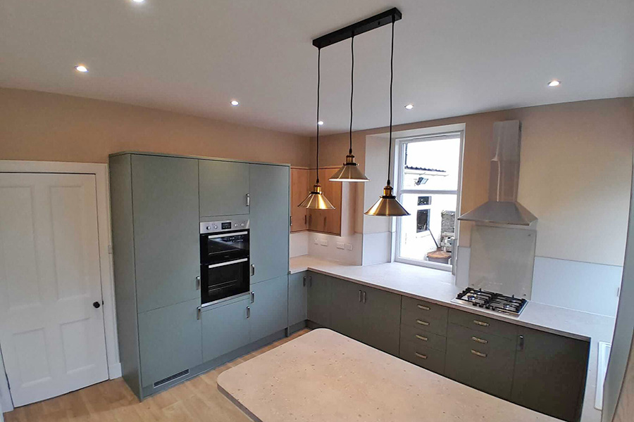 Modern kitchen renovation with sage green fitted units, white worktops, integrated appliances and pendant lighting, Farragon Joinery and Construction Services