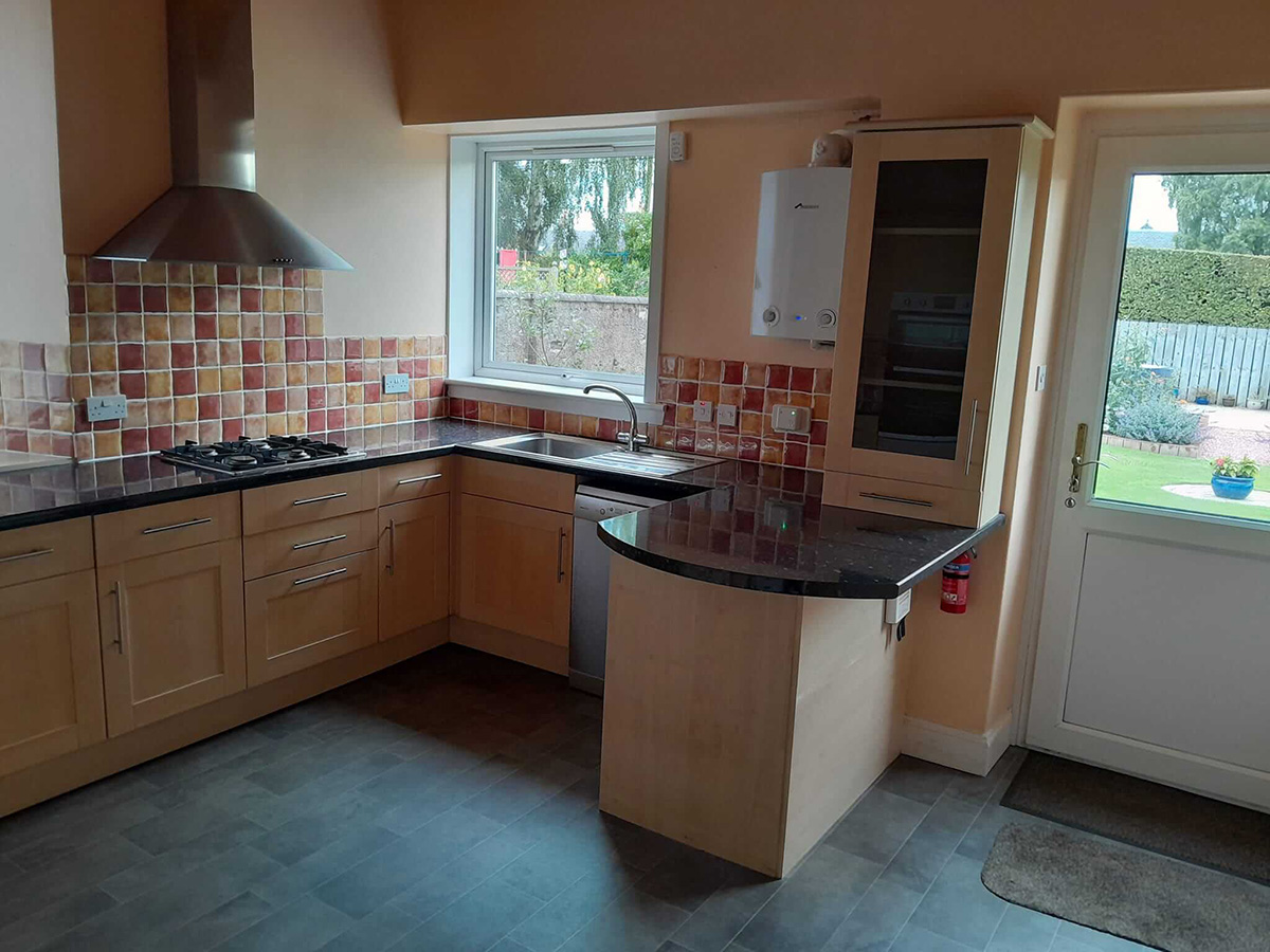 Original kitchen before renovation with light beech cabinets, colourful mosaic tile splashback and dark granite worktops