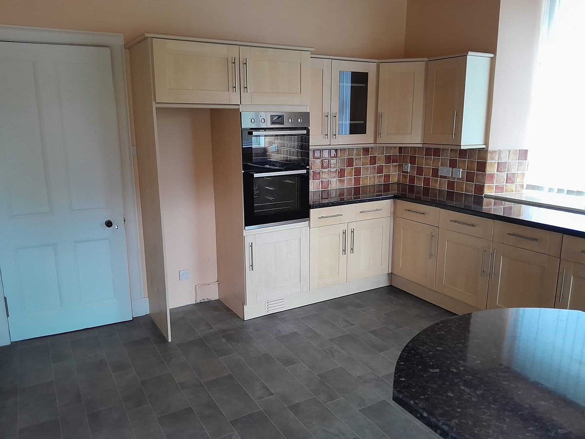 Original kitchen before renovation showing the oven tower unit, mosaic splashback and dark slate floor