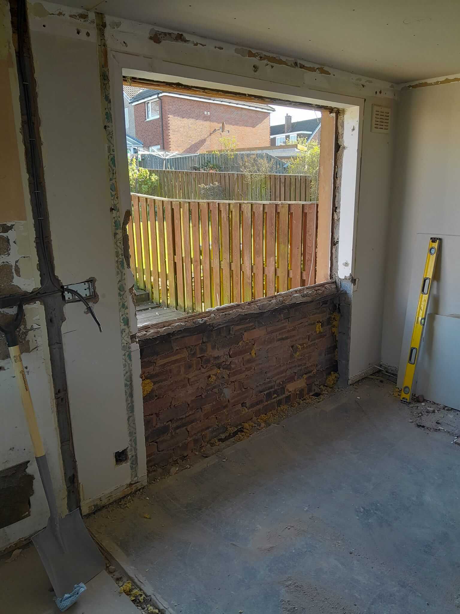 Kitchen window opening being enlarged during construction, showing exposed brickwork below