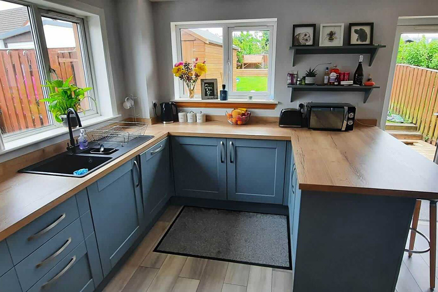 Open-plan kitchen with blue-grey shaker units, solid wood worktops and light wood flooring, Farragon Joinery and Construction Services