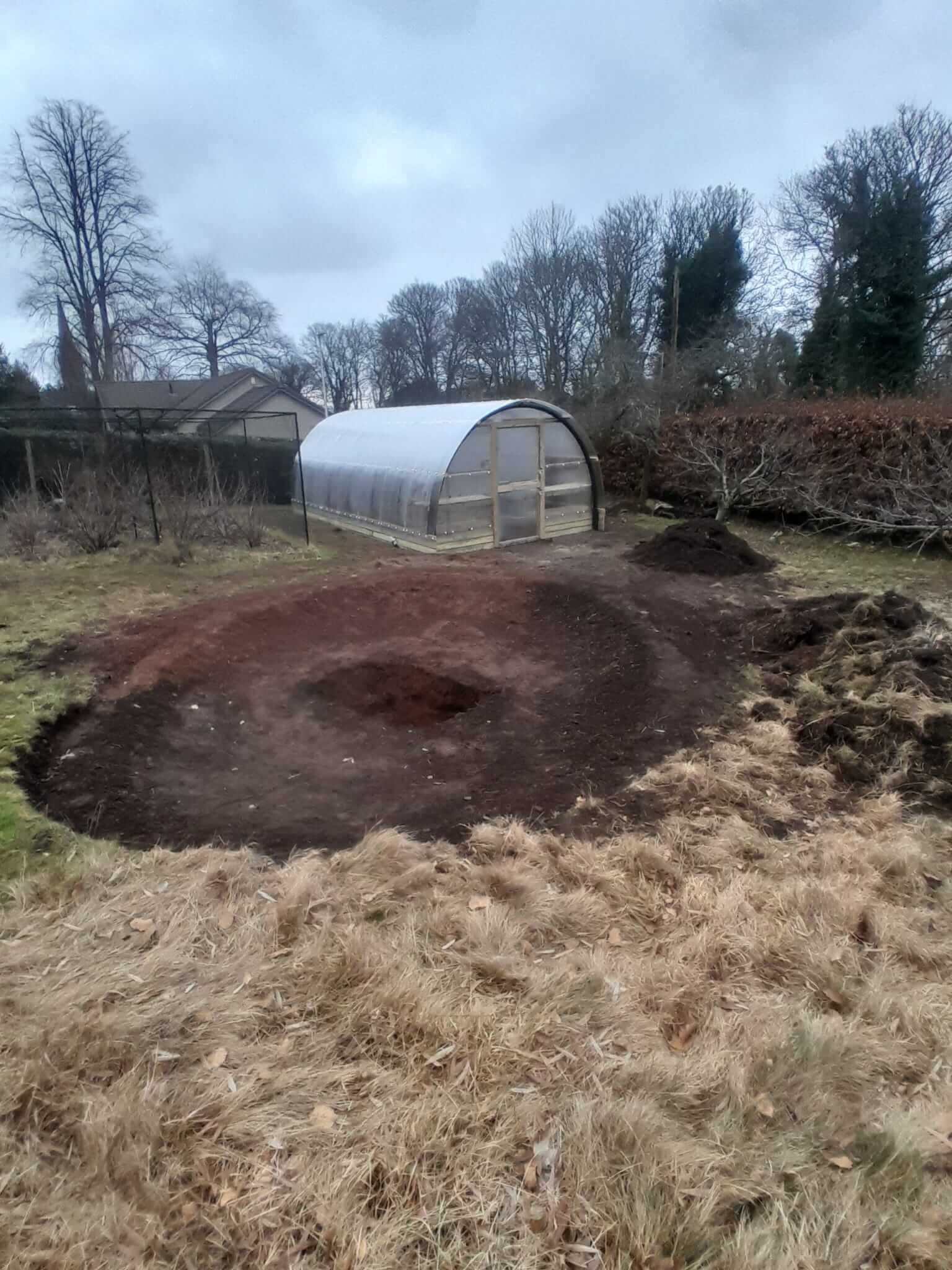 Poly Crub tunnel in context of garden with freshly graded groundworks for pond formation in foreground, Alyth
