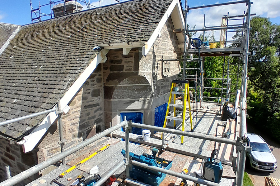 Residential extension under construction on a traditional stone house with scaffolding