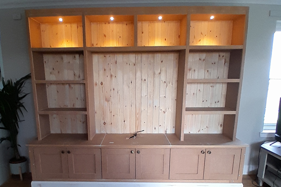 Bespoke built-in shelving unit with integrated lighting and cupboard doors by Farragon Joinery